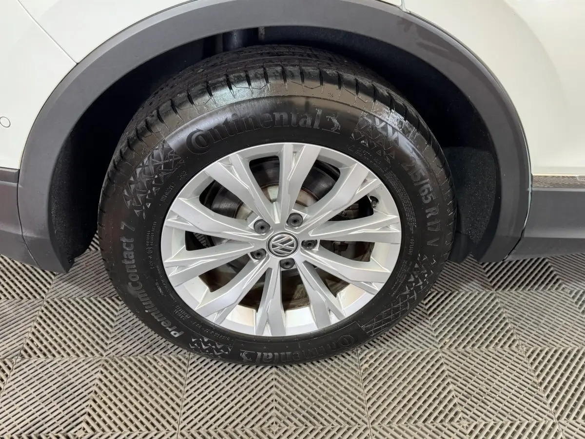Gros plan sur la roue avant droite d'un Volkswagen Tiguan blanc, mettant en valeur la jante alliage et le pneu Continental.