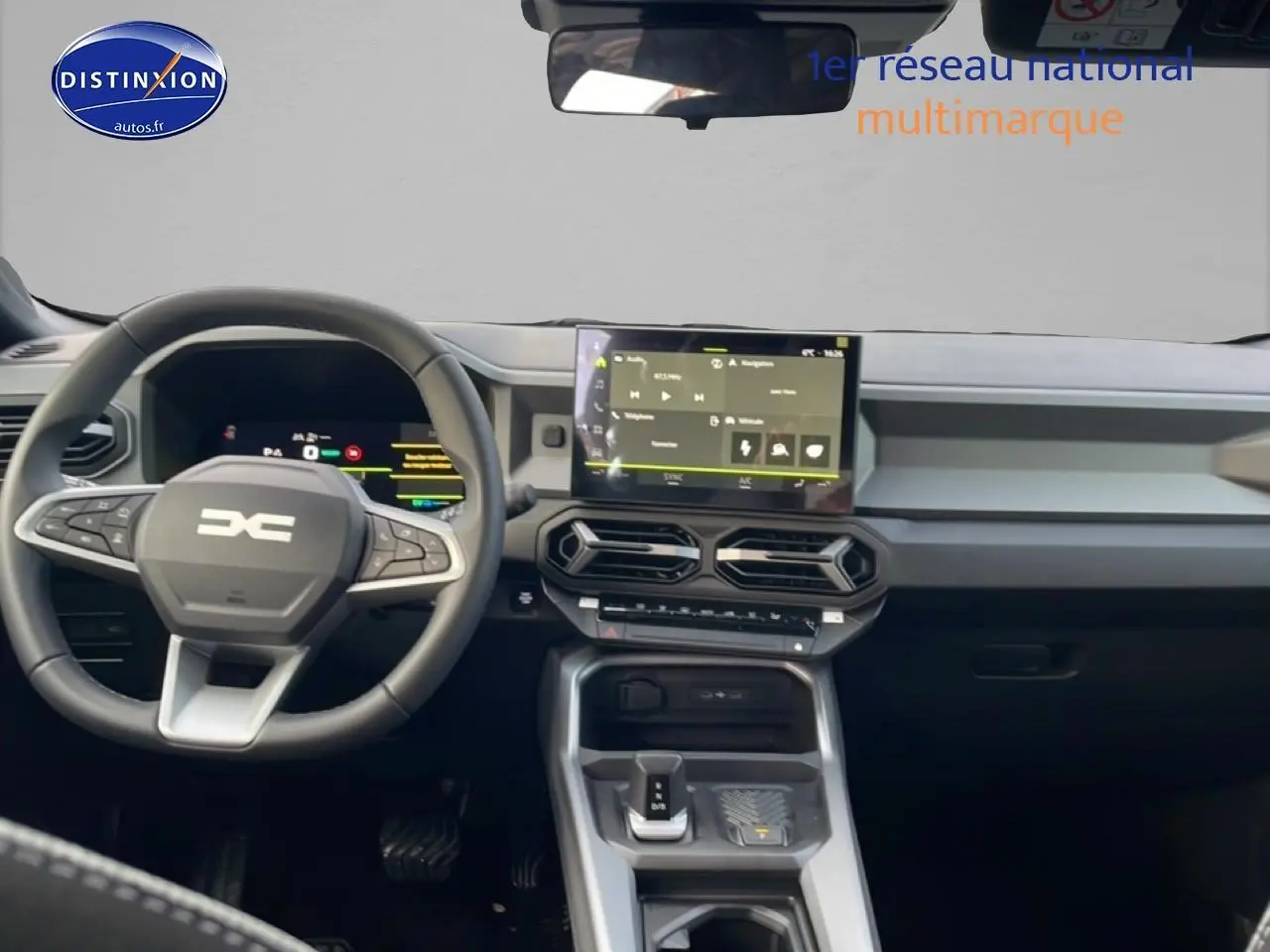 Vue intérieure frontale du tableau de bord et volant cuir du Dacia Bigster gris schiste avec écran tactile central et commandes modernes.