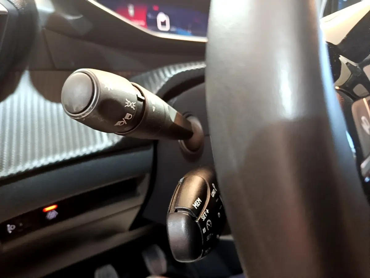 Gros plan sur le volant cuir et les commandes multifonctions du Peugeot 208 jaune, vue côté conducteur.