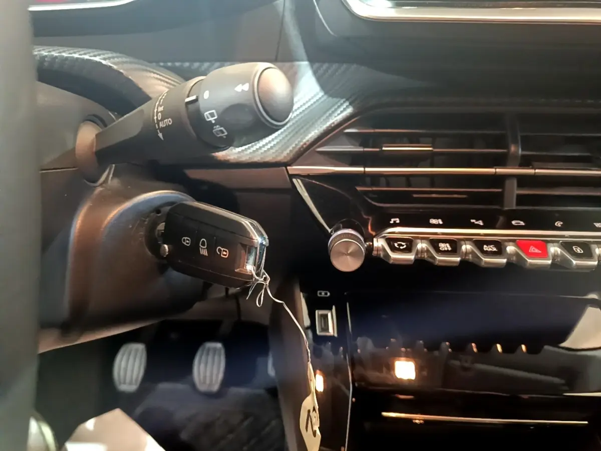 Gros plan sur le tableau de bord noir et la clé insérée dans le contacteur d'une Peugeot 208, côté conducteur.