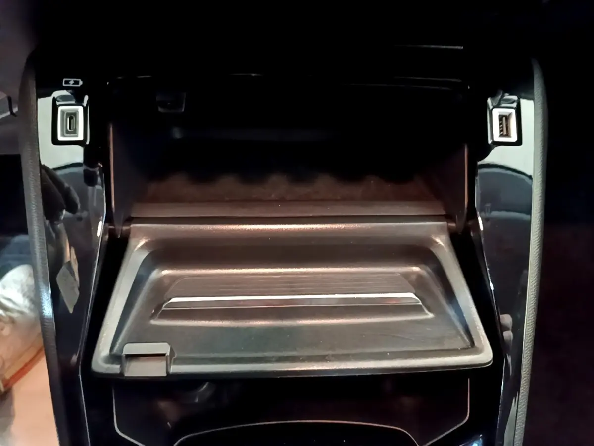 Vue rapprochée de la console centrale noire avec ports USB ouverts dans une Peugeot 208 jaune 2023.