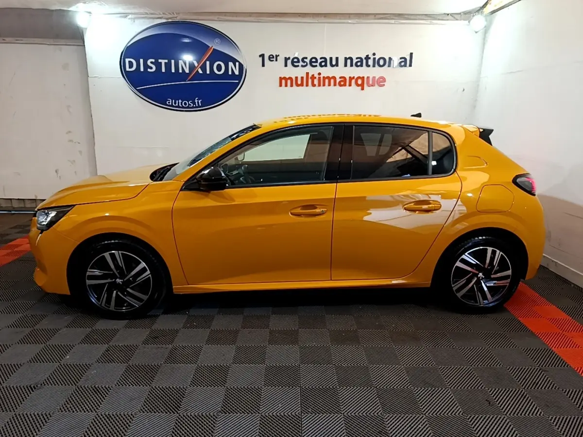 Peugeot 208 PureTech 100 S&S Allure Pack jaune vue de profil côté gauche dans un showroom intérieur.