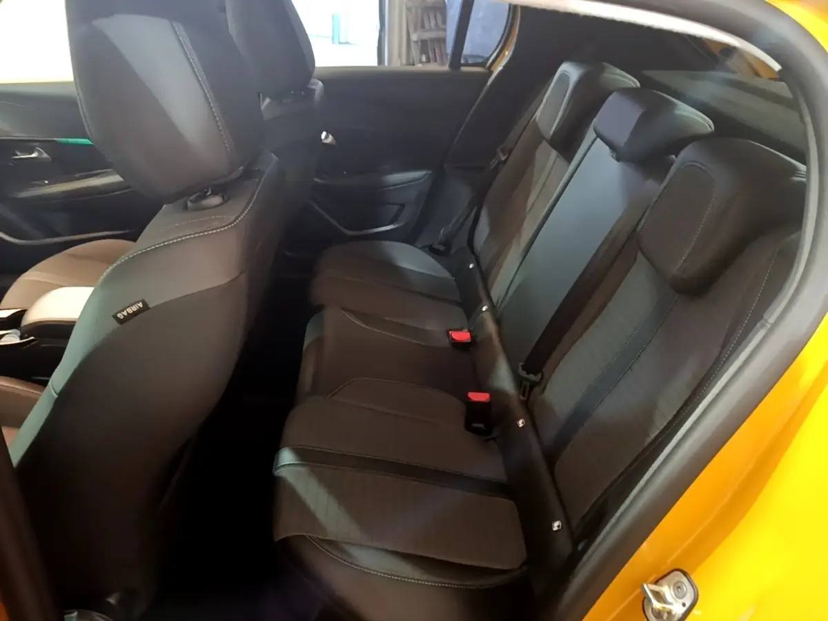 Vue intérieure côté droit montrant la banquette arrière noire de la Peugeot 208 jaune 2023 PureTech Allure Pack.