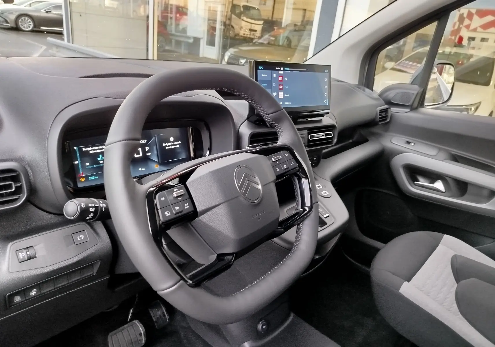 Vue intérieure côté conducteur du Citroën Berlingo 2025, volant multifonction et écran tactile central visibles.