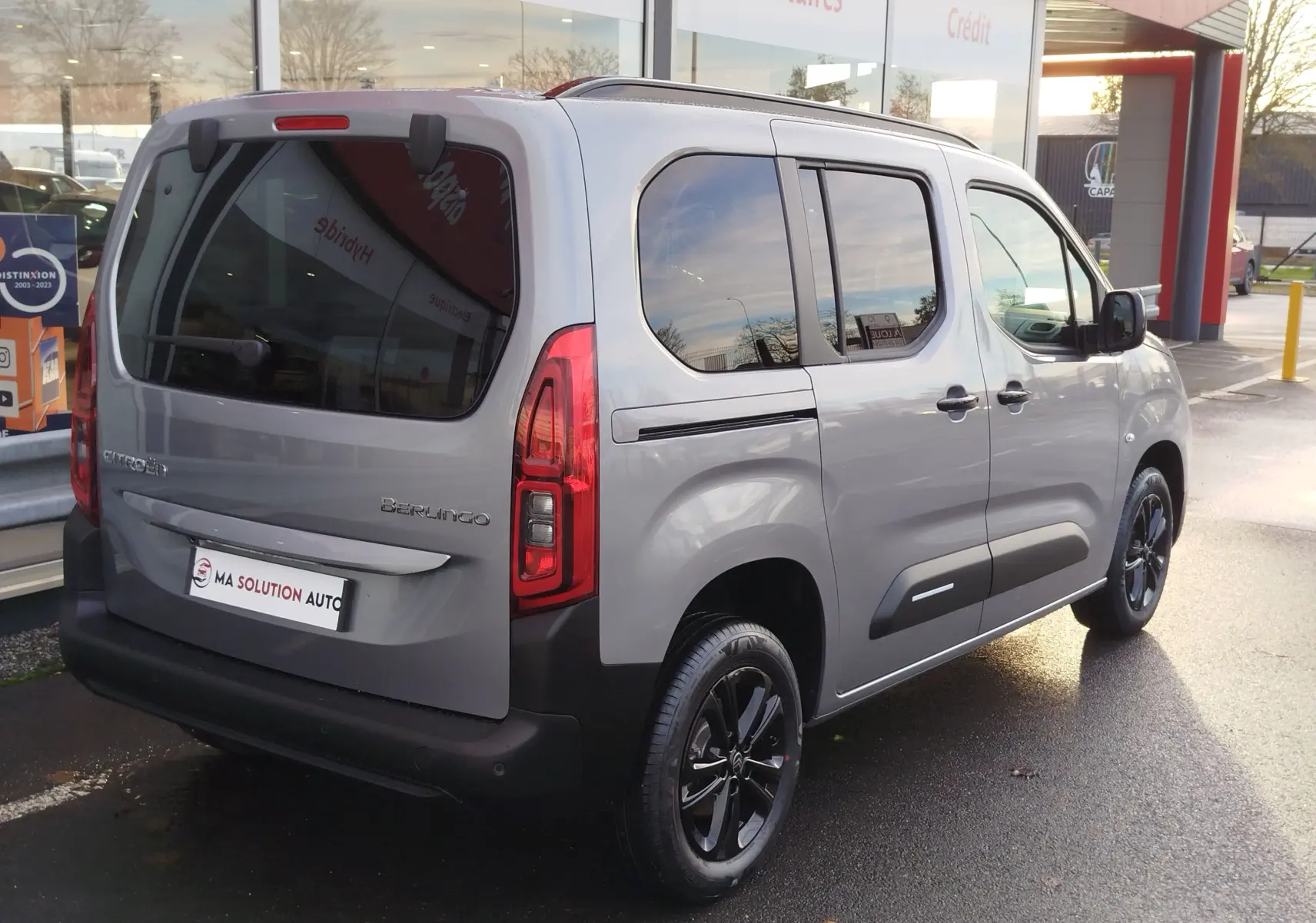 Vue 3/4 arrière droite d'un Citroën Berlingo gris acier 2025 avec vitres teintées et jantes noires.