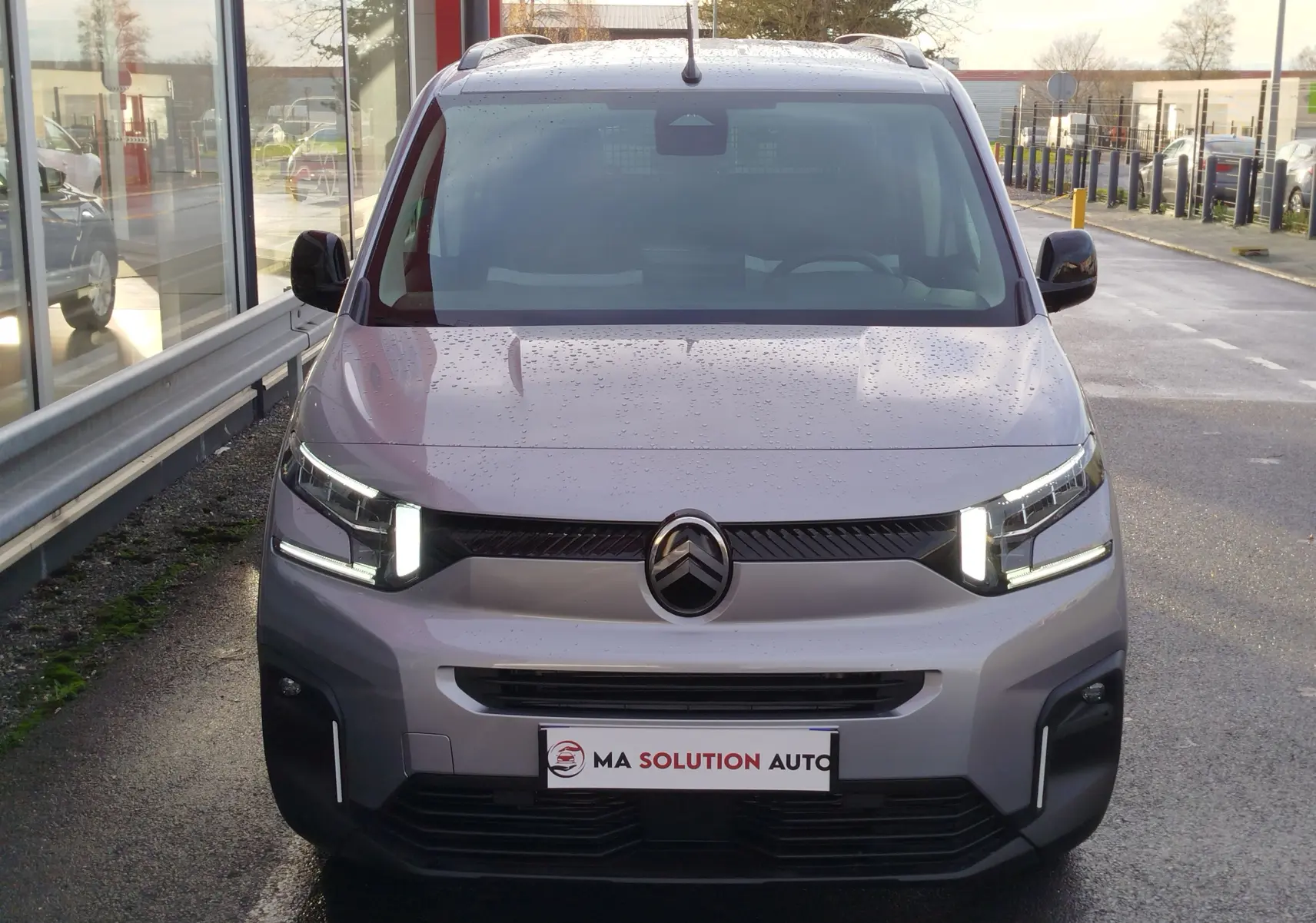 Vue avant d'un Citroën Berlingo gris acier 2025 avec phares LED allumés et calandre noire distinctive.