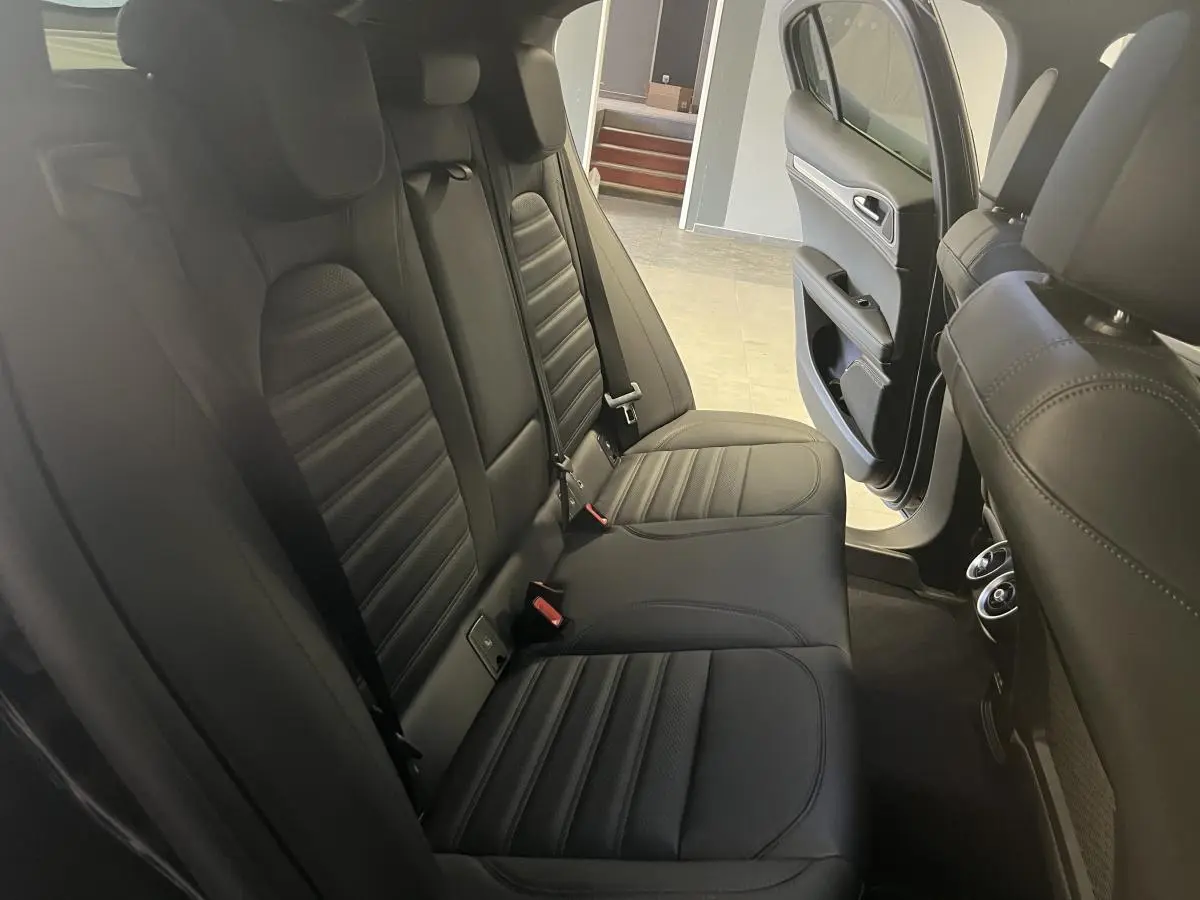 Vue intérieure arrière côté droit de l'Alfa Romeo Stelvio 2024 avec sièges sport en cuir noir et porte ouverte.