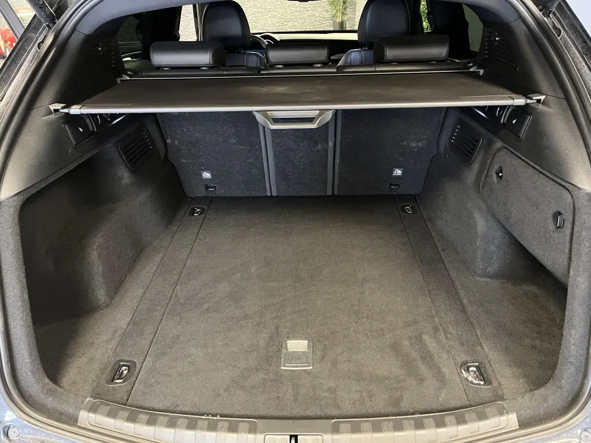 Vue du coffre arrière ouvert de l'Alfa Romeo Stelvio noir avec cache-bagages et banquette arrière visible.