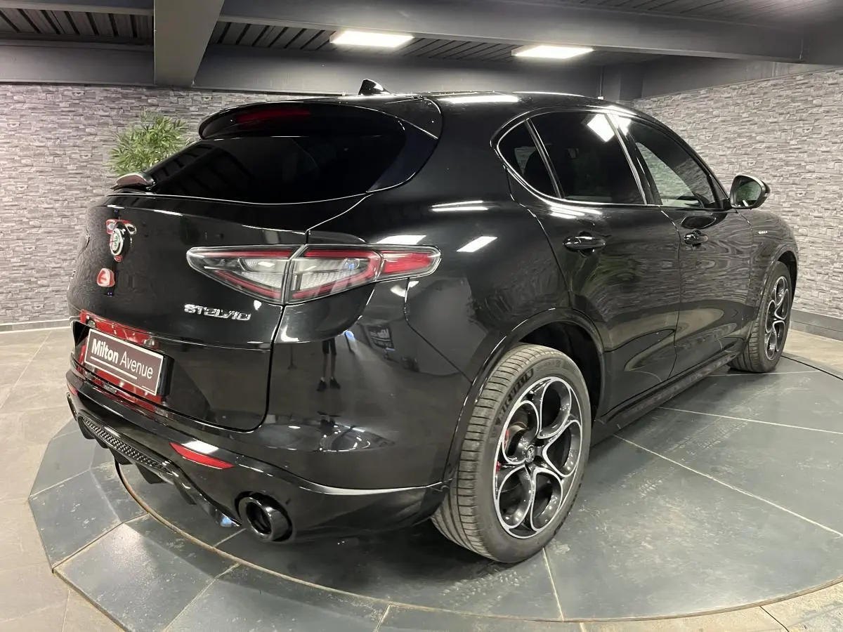 Vue 3/4 arrière droite de l'Alfa Romeo Stelvio Veloce noire avec jantes alliage 20 pouces et vitres surteintées.