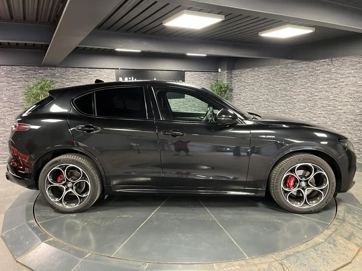 Vue de profil côté gauche d'un Alfa Romeo Stelvio Veloce noir métallisé avec jantes alliage 20 pouces et étriers rouges.