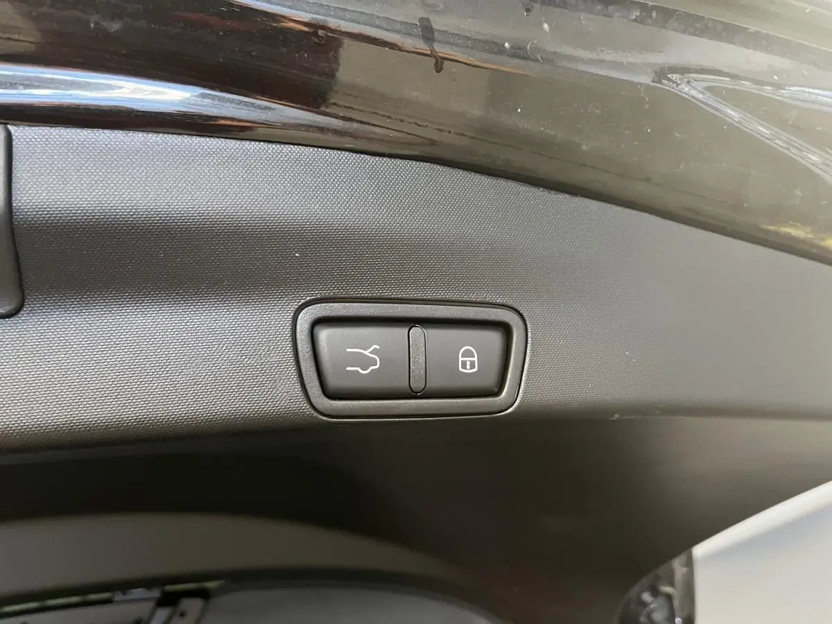 Gros plan sur le bouton d'ouverture et de verrouillage du hayon électrique du coffre d'un Alfa Romeo Stelvio noir.