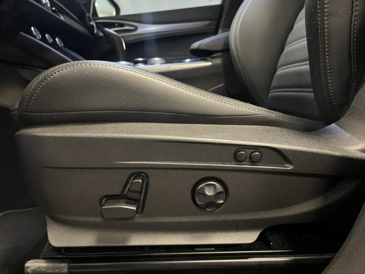 Gros plan sur les commandes de réglage électrique du siège avant en cuir noir de l'Alfa Romeo Stelvio Veloce 2024.