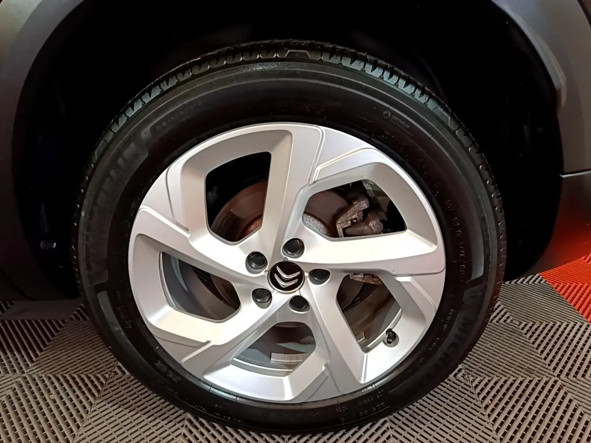 Gros plan sur la roue avant droite avec jante argentée et logo Citroën sur un C5 Aircross noir.