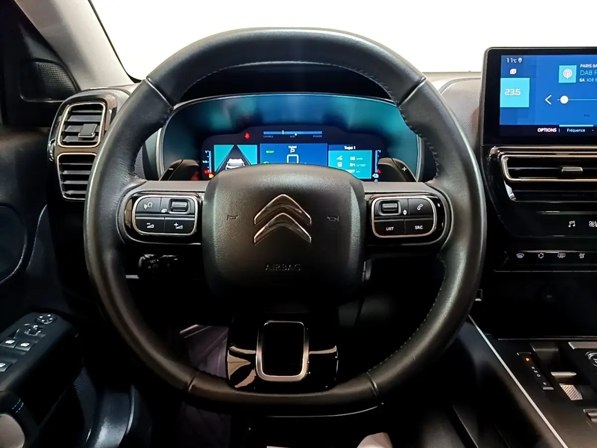 Vue intérieure centrée sur le volant cuir noir et le combiné numérique du tableau de bord du Citroën C5 Aircross hybride.