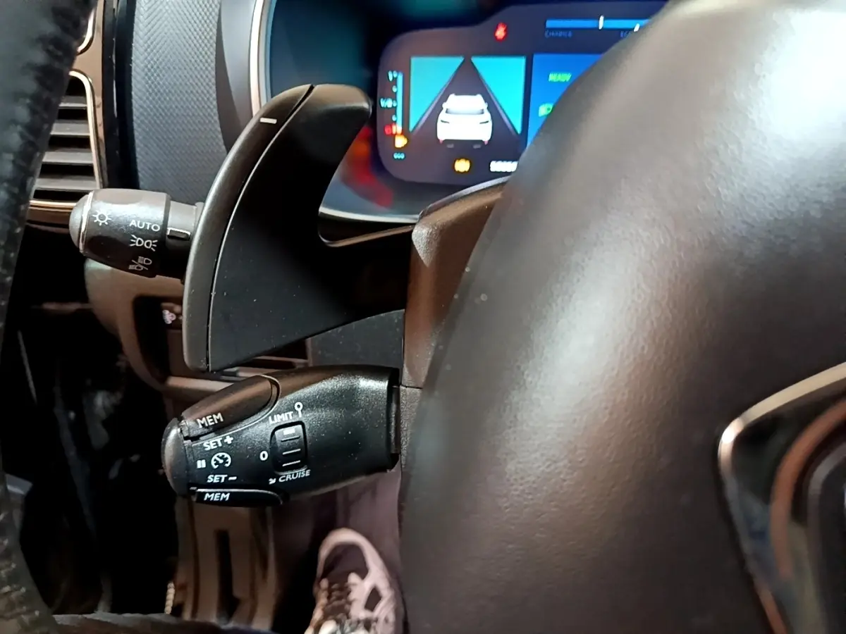 Gros plan sur la commande de régulateur de vitesse et levier de clignotant du tableau de bord noir du Citroën C5 Aircross hybride.