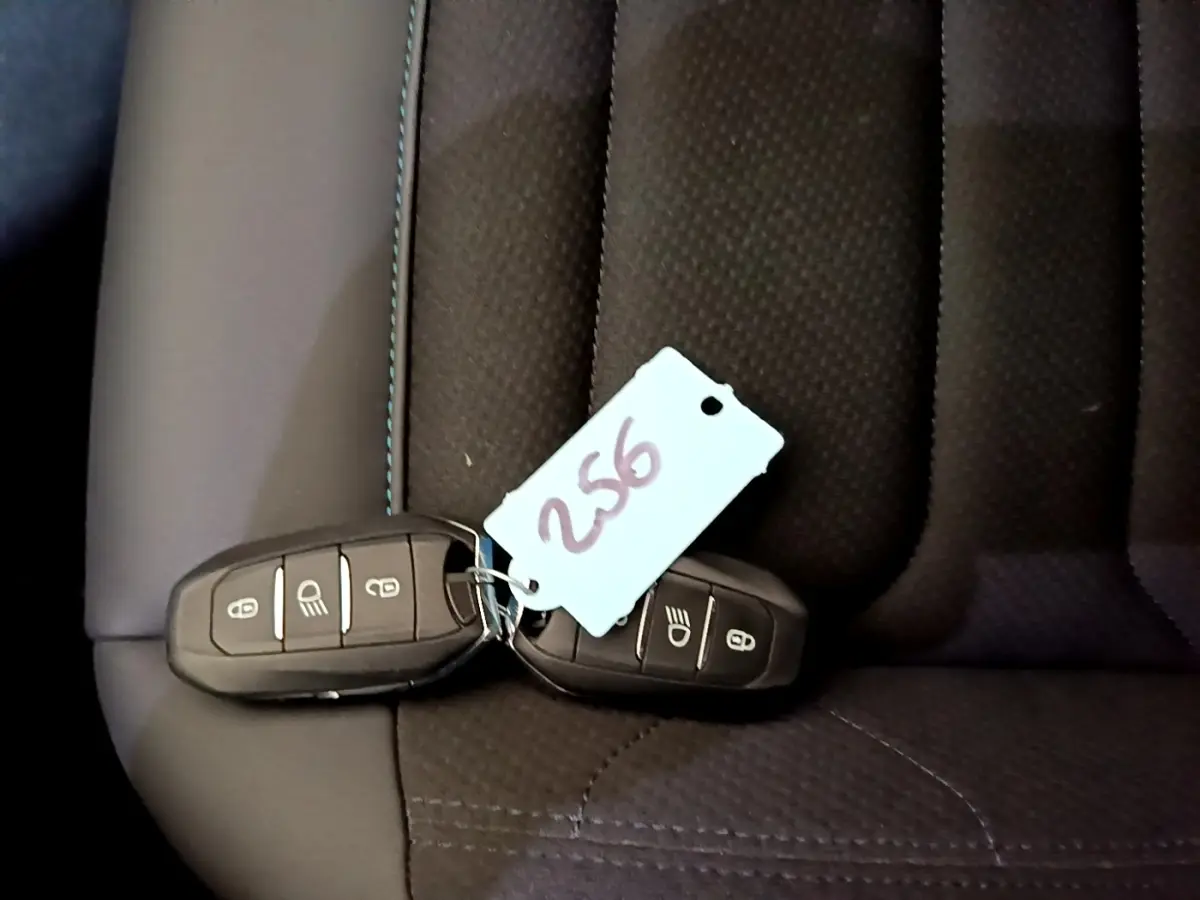 Gros plan sur deux clés noires avec étiquette posées sur un siège en tissu noir du Citroën C5 Aircross hybride rechargeable.