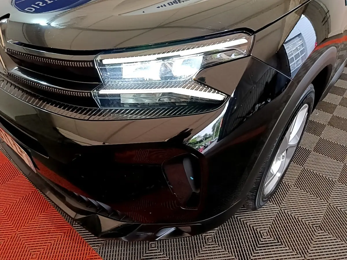 Gros plan sur l'avant droit noir brillant du Citroën C5 Aircross hybride rechargeable avec phares LED allumés.