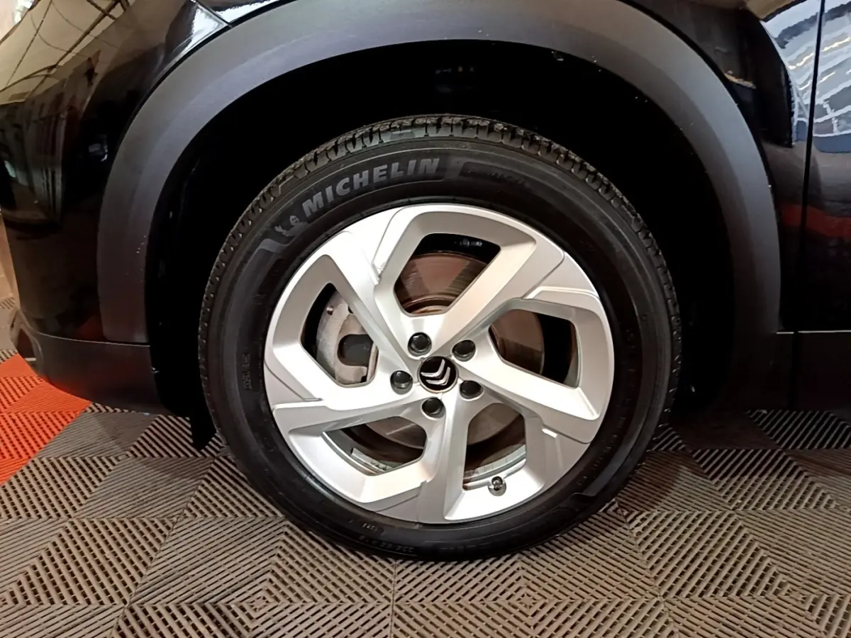 Gros plan sur la roue avant gauche noire du Citroën C5 Aircross hybride rechargeable avec jante argentée et pneu Michelin.