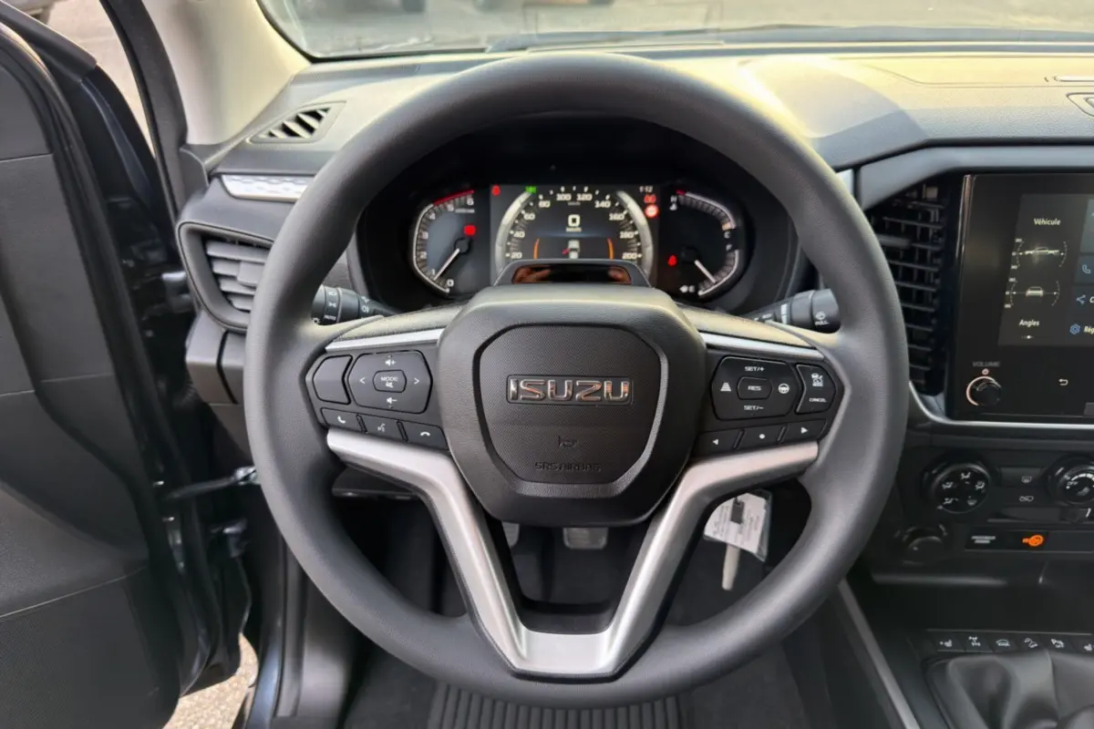 Vue centrée sur le volant multifonctions noir de l'Isuzu D-MAX 2026 avec tableau de bord et écran tactile visibles.