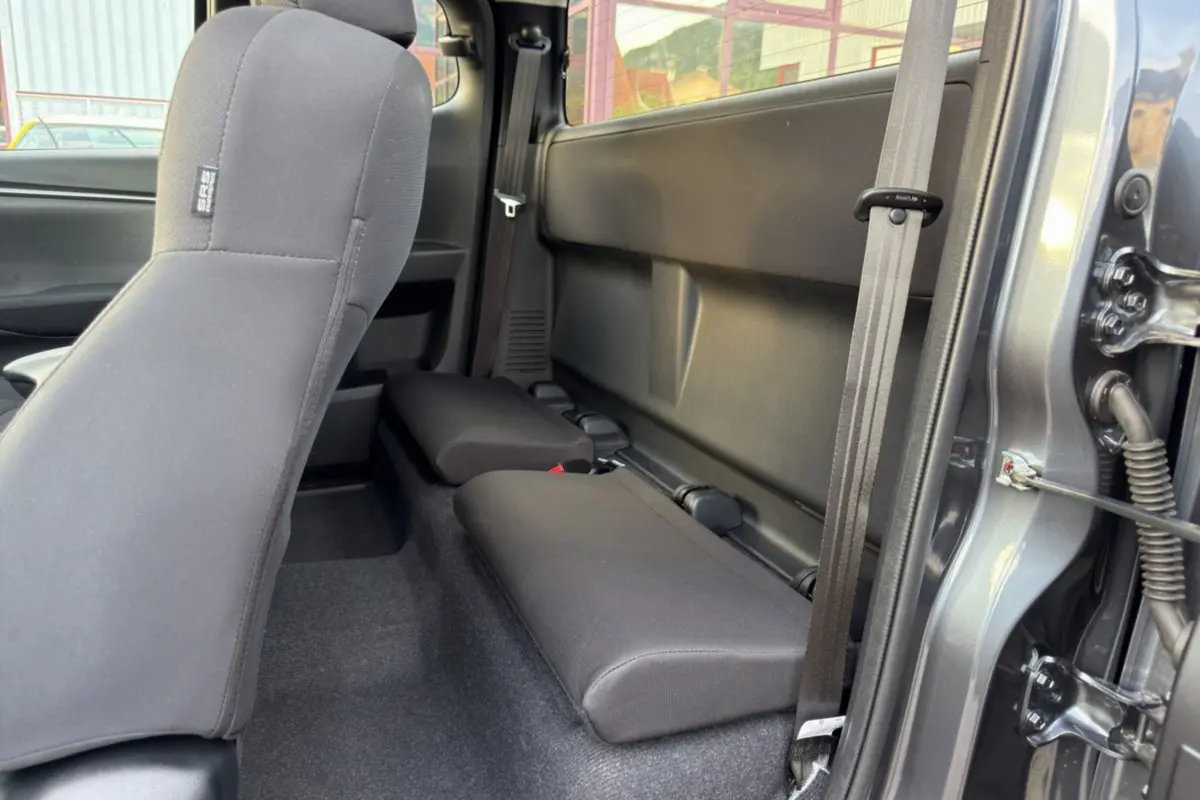 Vue latérale droite sur les sièges arrière strapontins en tissu gris du pick-up Isuzu D-MAX Obsidian Grey Mica.