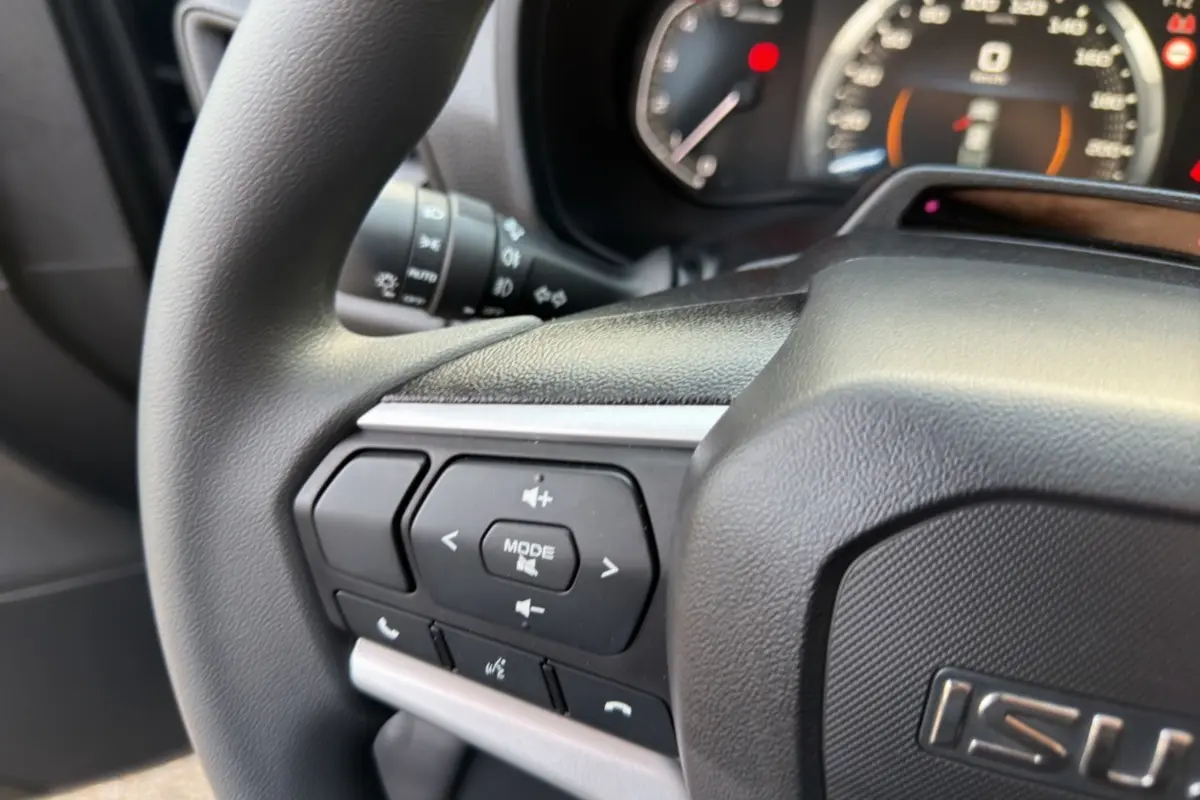 Gros plan sur le volant multifonctions noir de l'Isuzu D-MAX 2026 avec commandes audio et téléphone intégrées.