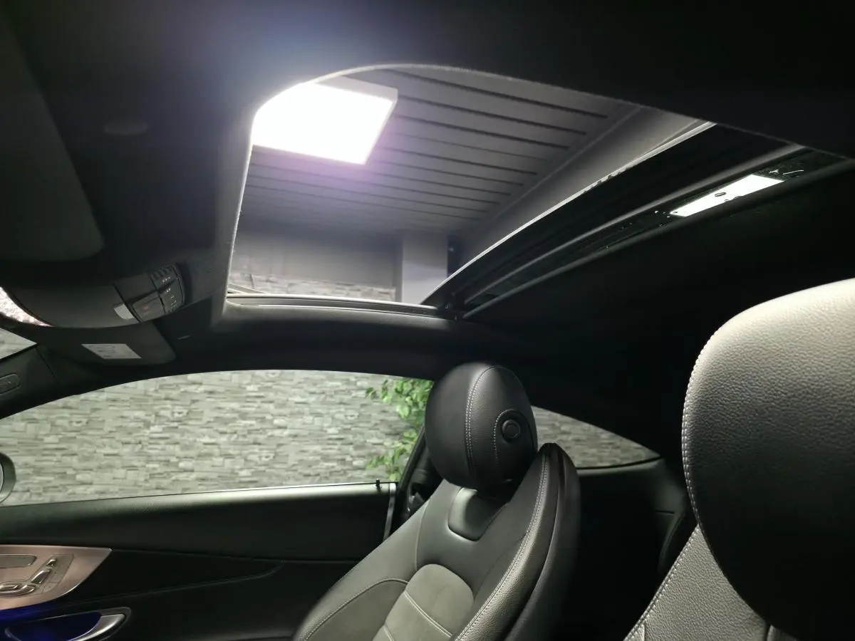 Intérieur noir du coupé Mercedes Classe C 220 d 2019, vue sur siège avant droit et toit ouvrant panoramique ouvert.