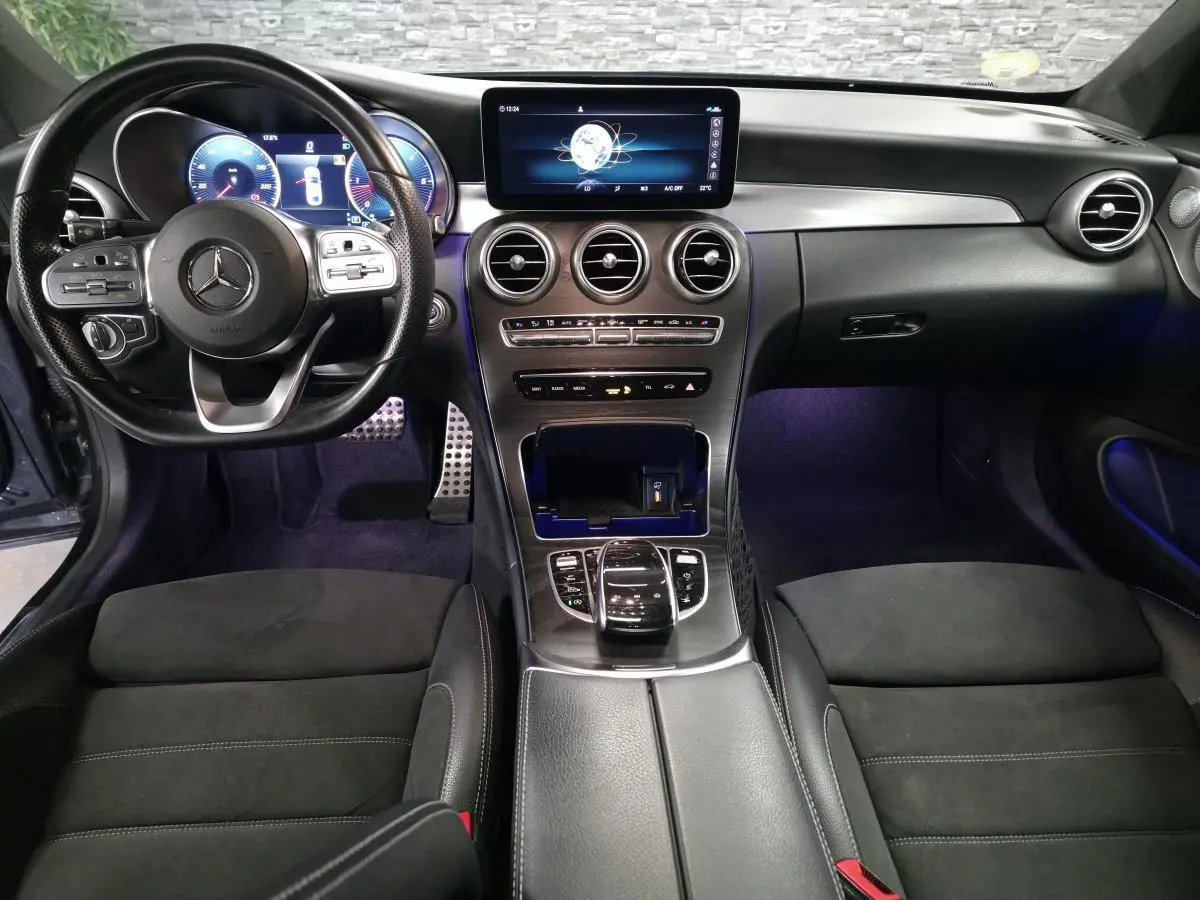 Vue intérieure avant de la Mercedes Classe C Coupé 2019, tableau de bord noir avec écran digital et volant multifonction.
