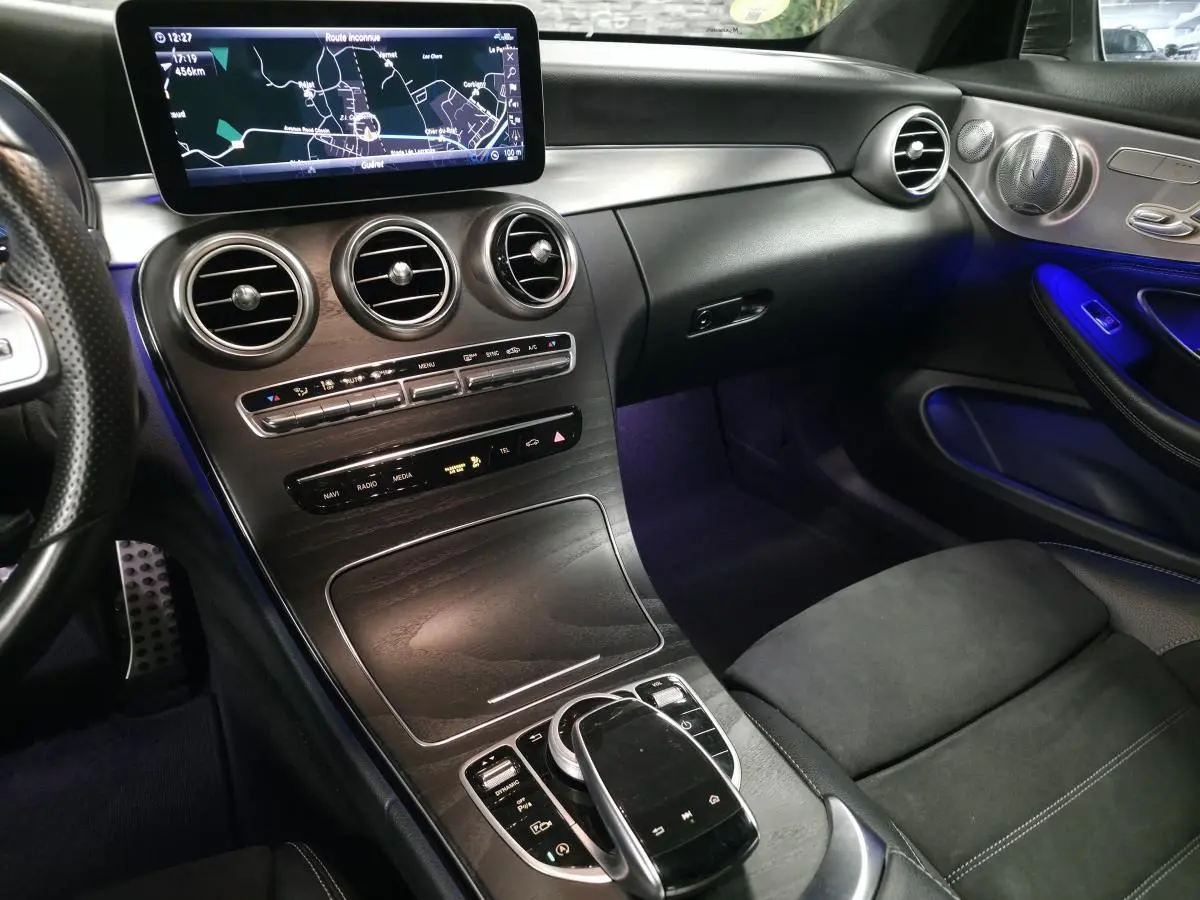 Vue intérieure côté passager de la Mercedes Classe C Coupé AMG Line 2019, avec éclairage d'ambiance bleu et finitions noires.