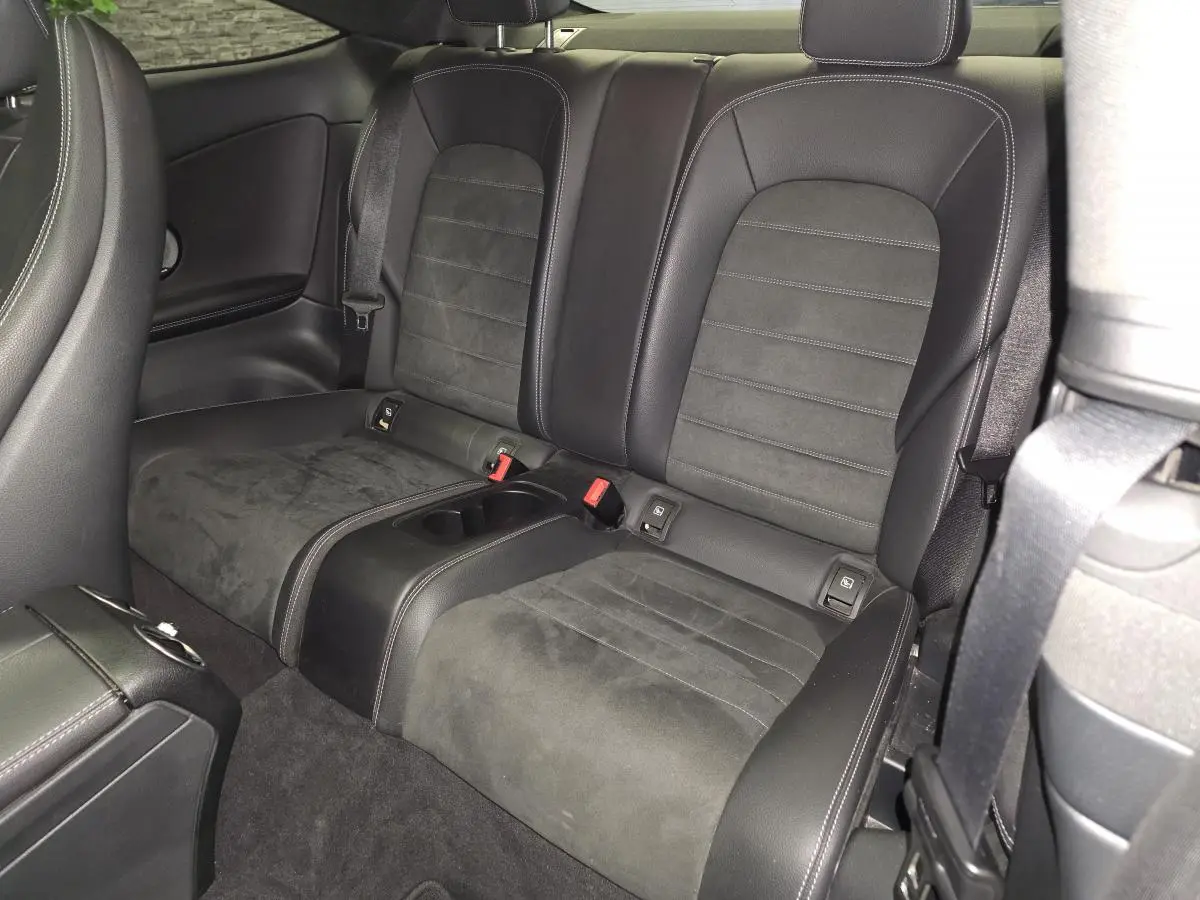 Vue intérieure arrière montrant les sièges en cuir noir et alcantara du coupé Mercedes Classe C gris.