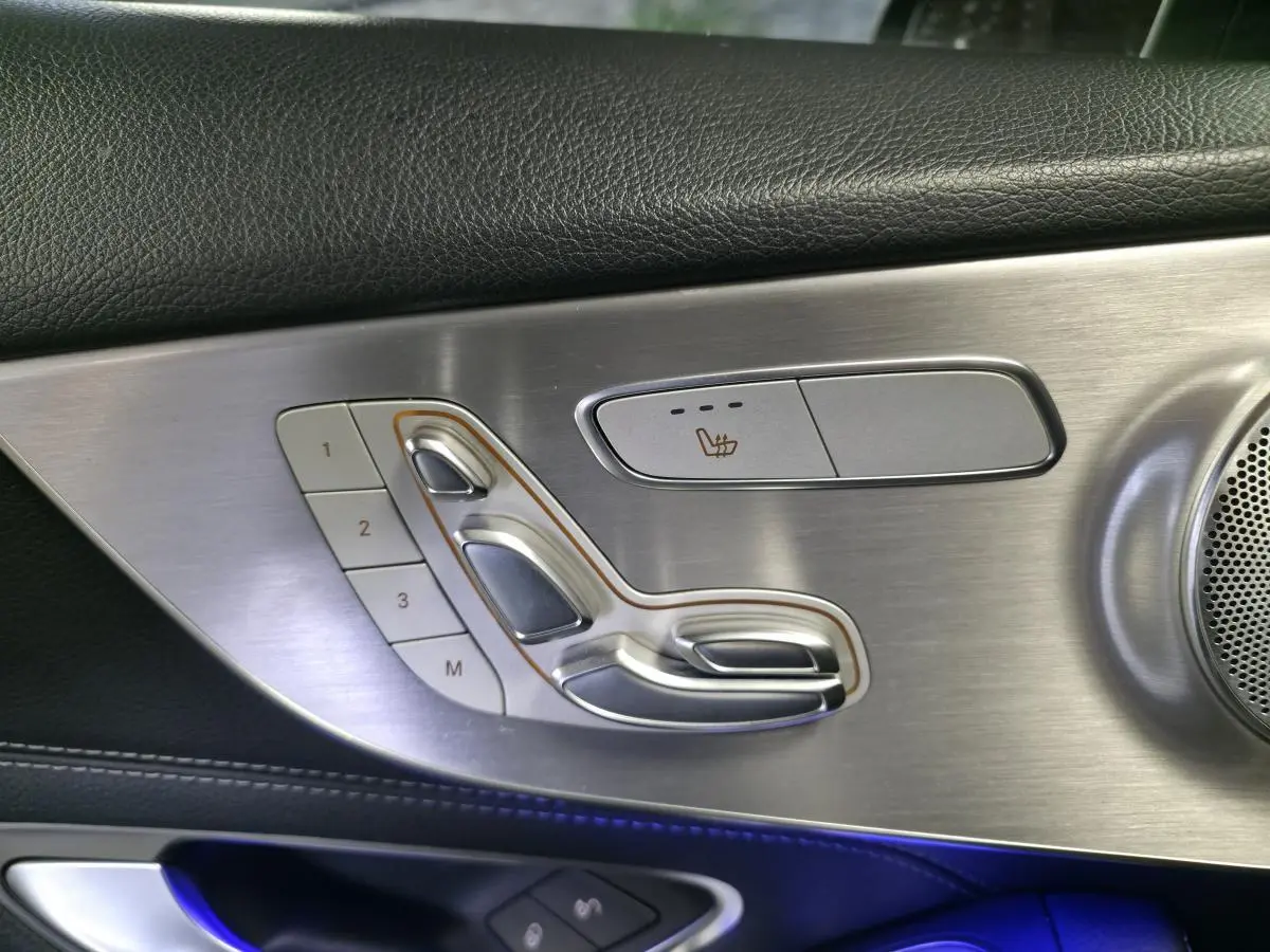 Détail du panneau de porte côté gauche en aluminium brossé avec commandes de siège chauffant et mémoire sur Mercedes Classe C Coupé gris.