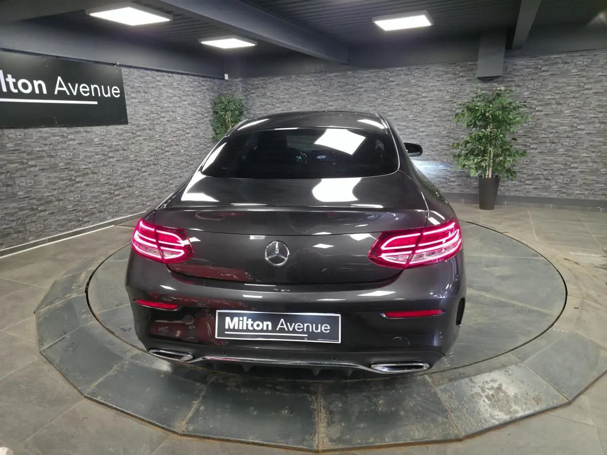 Vue arrière d'une Mercedes Classe C Coupé gris métallisé avec feux LED allumés dans un showroom.