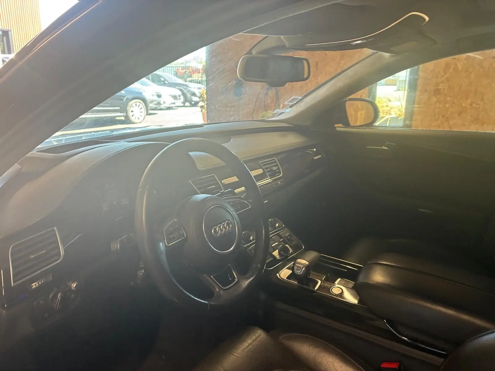 Vue intérieure côté conducteur de l'Audi A8 noire 2016, mettant en valeur le volant multifonction et la console centrale.