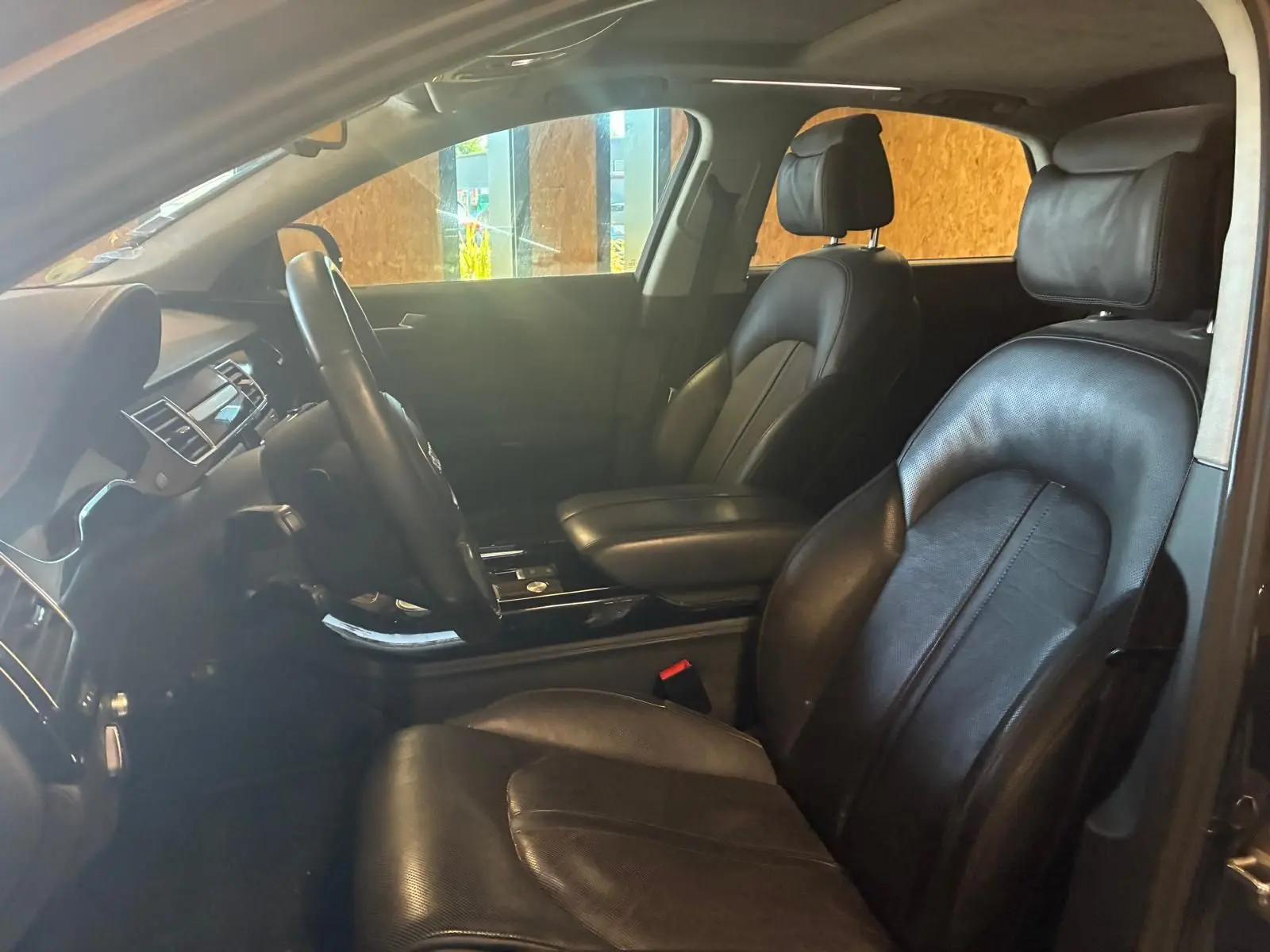 Vue intérieure côté gauche de l’Audi A8 2016 noire, montrant les sièges en cuir et le tableau de bord élégant.