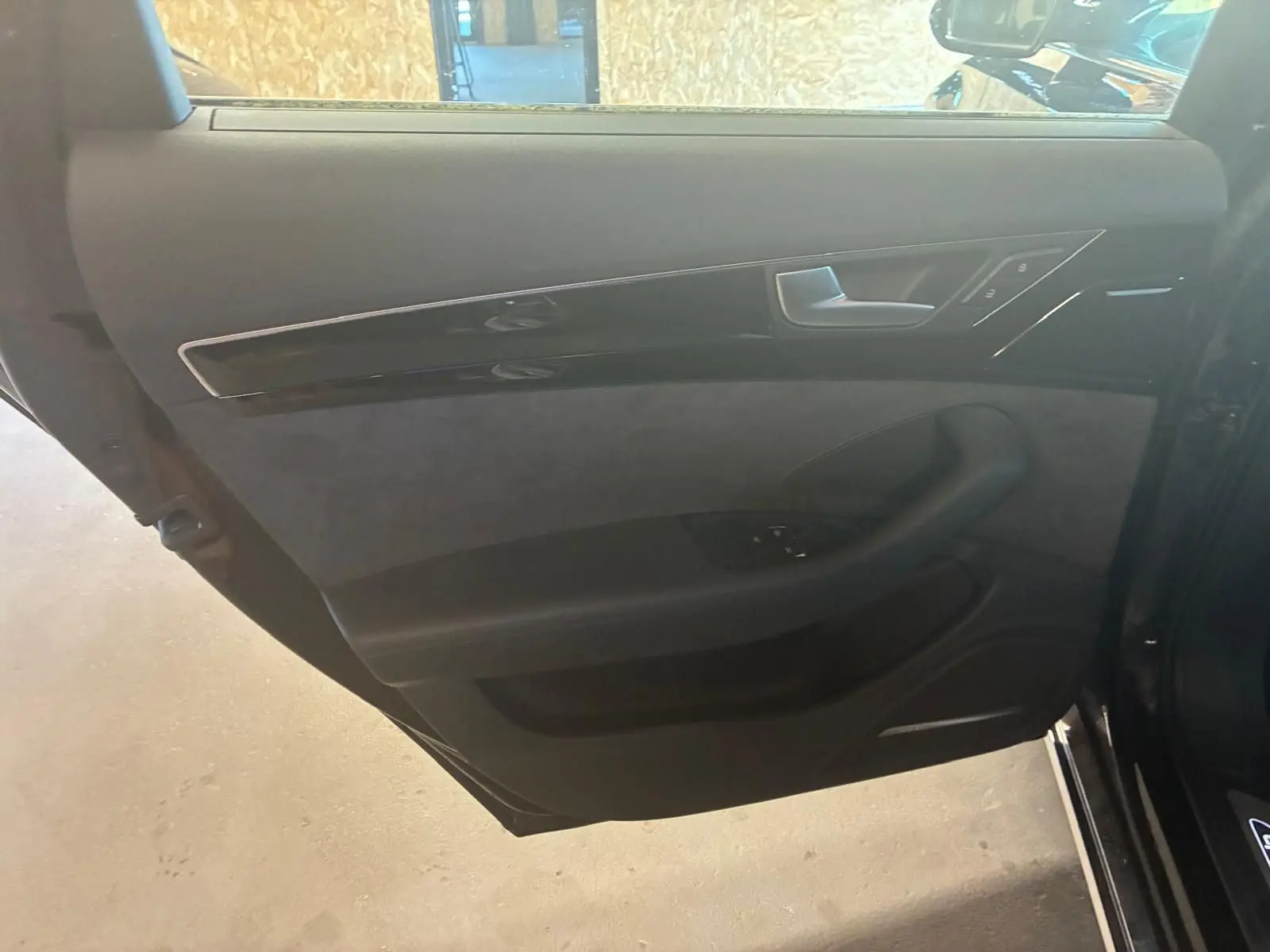 Vue intérieure de la porte arrière droite noire d'une Audi A8 2016 avec garniture en cuir et inserts brillants.