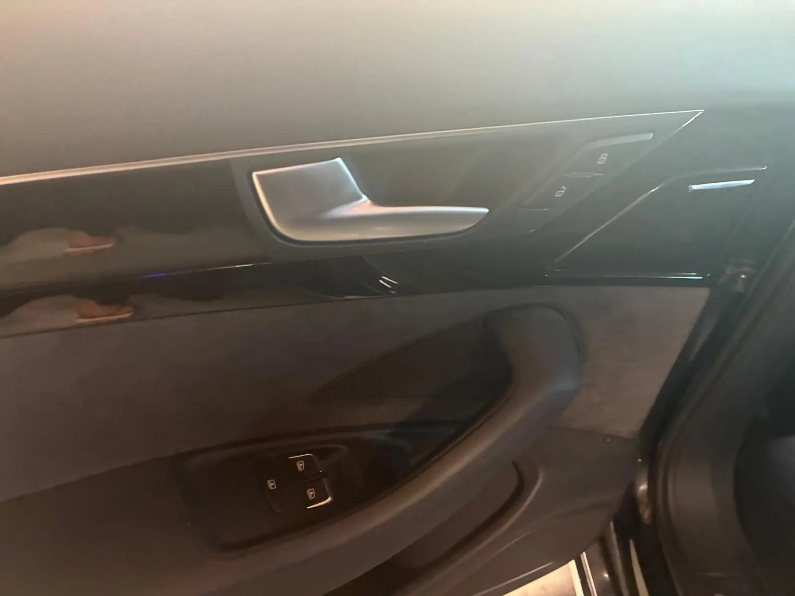 Détail de la porte intérieure côté gauche de l’Audi A8 noire 2016, avec commandes de verrouillage et poignée argentée.