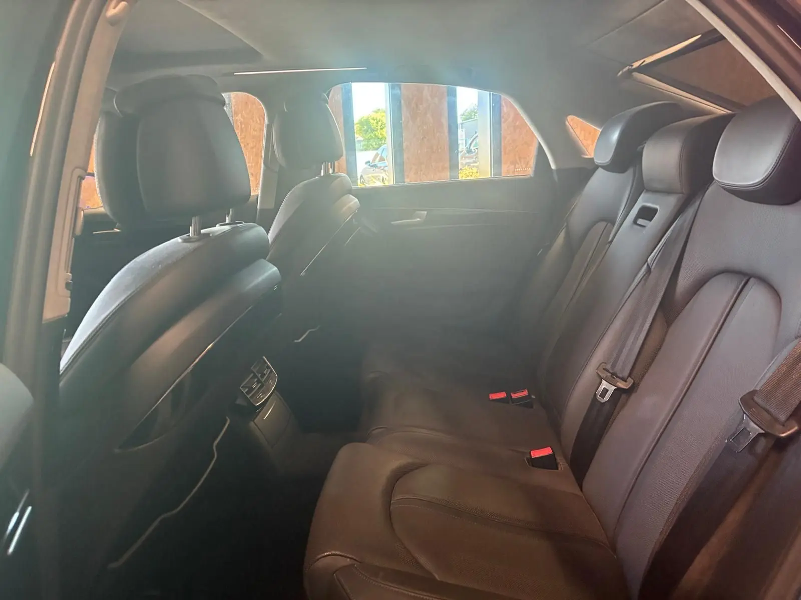 Vue intérieure arrière droite de l'Audi A8 2016 noire, montrant les sièges arrière en cuir et les ceintures de sécurité.
