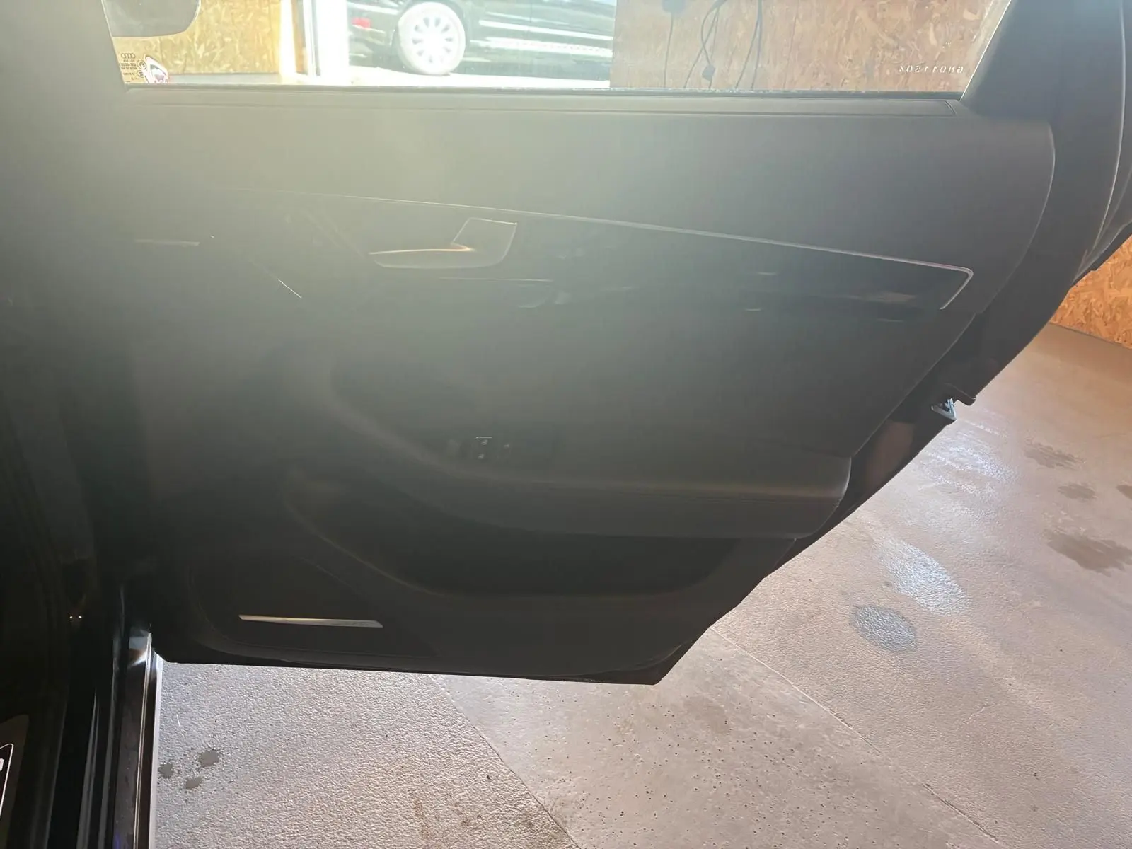 Vue intérieure de la porte avant gauche noire d'une Audi A8 2016, avec garniture en cuir et commandes de fenêtre.