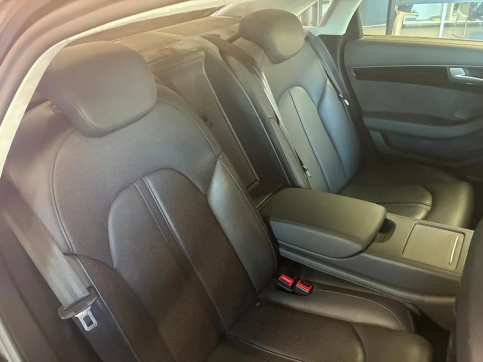 Vue intérieure côté droit des sièges arrière en cuir noir de l'Audi A8 2016 avec accoudoir central et ceintures visibles.