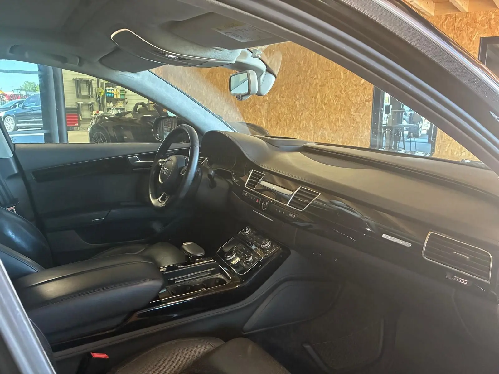 Intérieur noir de l'Audi A8 2016 vu côté conducteur, mettant en valeur le tableau de bord et la console centrale.