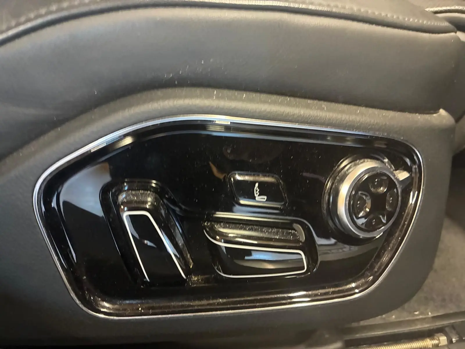 Gros plan sur les commandes de réglage électrique du siège côté gauche d'une Audi A8 noire 2016.