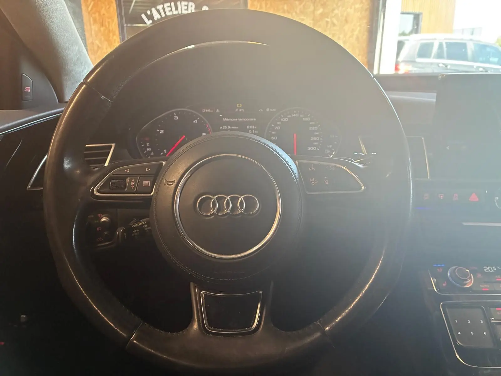 Vue rapprochée du volant noir de l'Audi A8 2016 avec commandes intégrées et tableau de bord numérique.