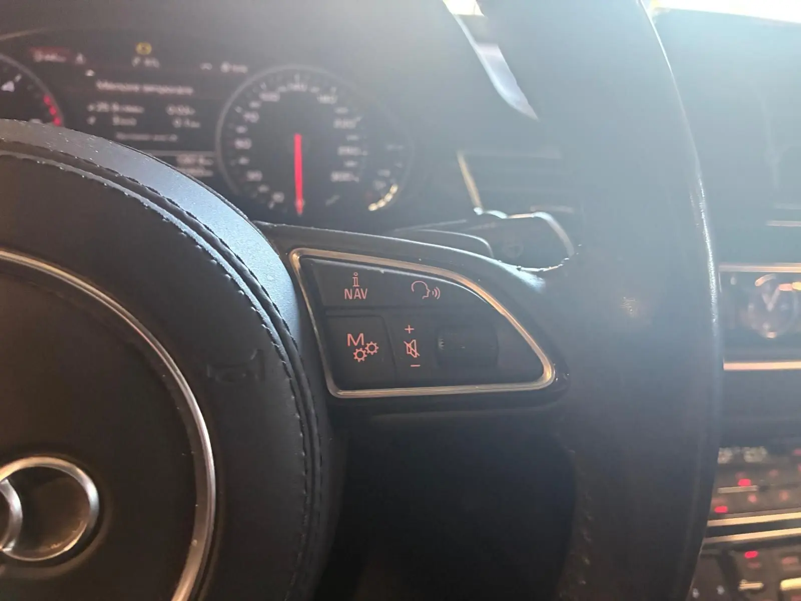 Vue rapprochée du volant noir de l'Audi A8 2016, avec commandes audio et navigation illuminées en rouge.
