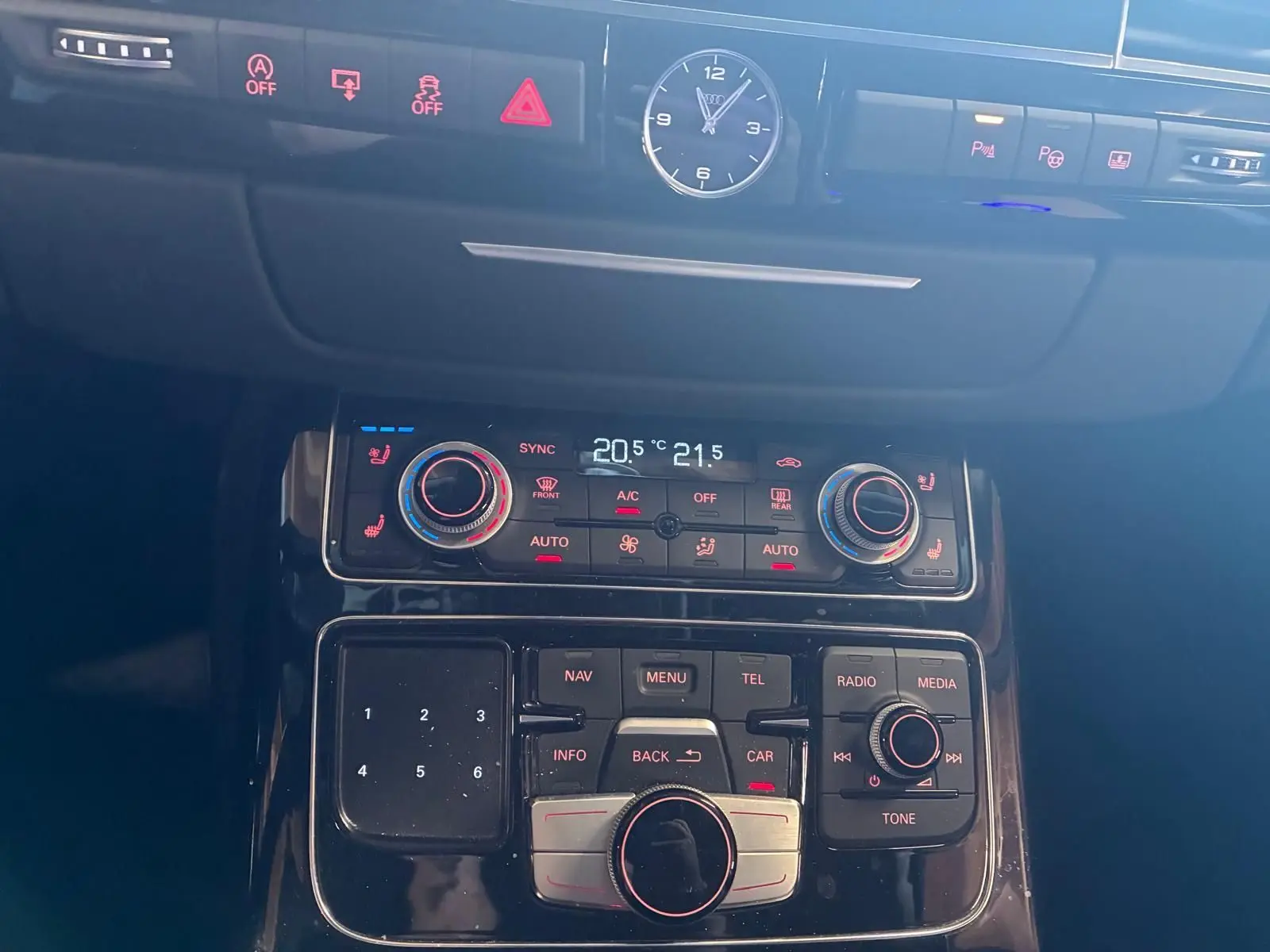 Vue rapprochée du tableau de bord noir de l'Audi A8 3.0 TDI 2016, avec horloge analogique et commandes climatisation digitales.