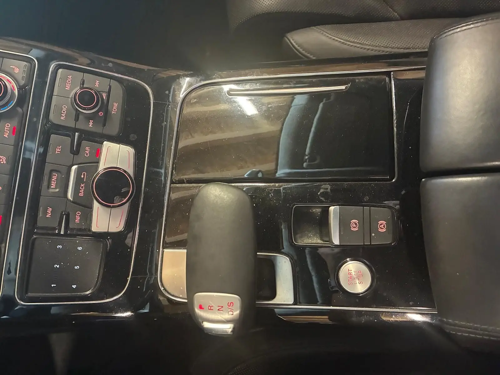 Vue rapprochée du levier de vitesses automatique et des commandes centrales noires de l’Audi A8 3.0 TDI 2016.