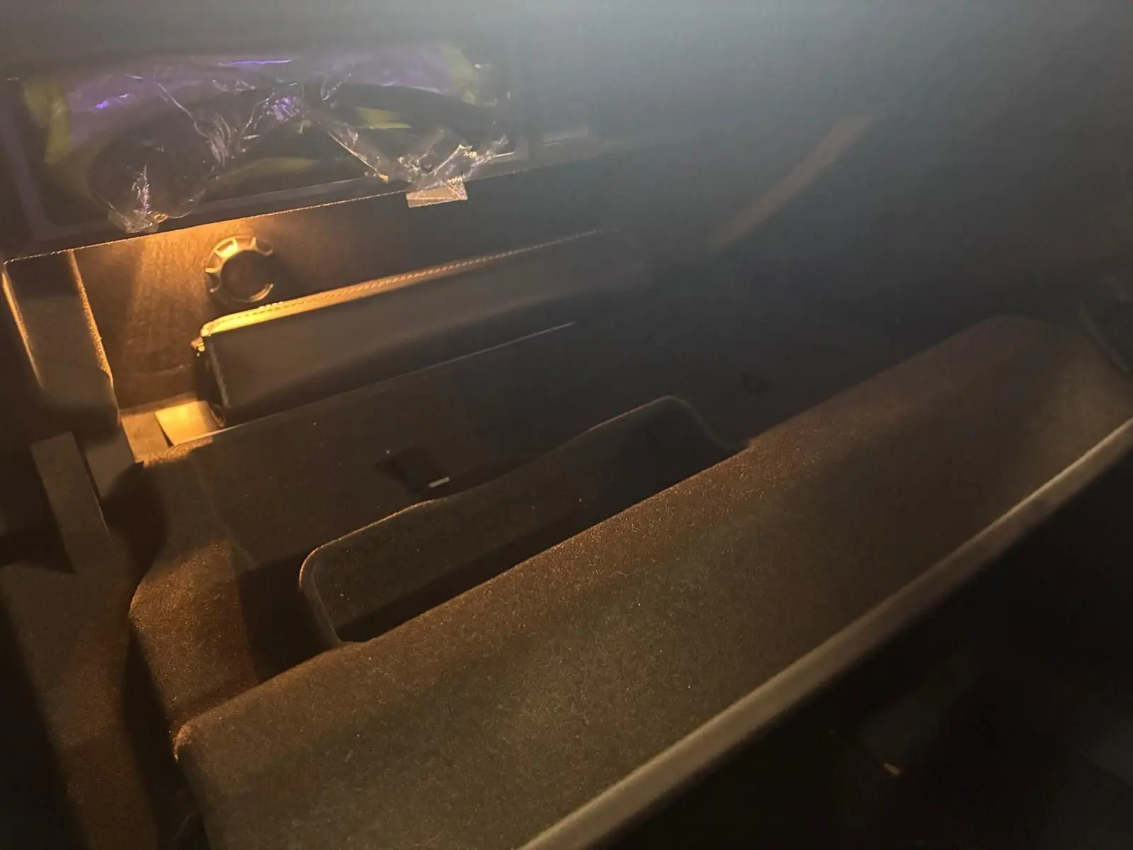 Intérieur du coffre noir d’une Audi A8 2016, vue en plongée avec éclairage tamisé sur la moquette et rangement.