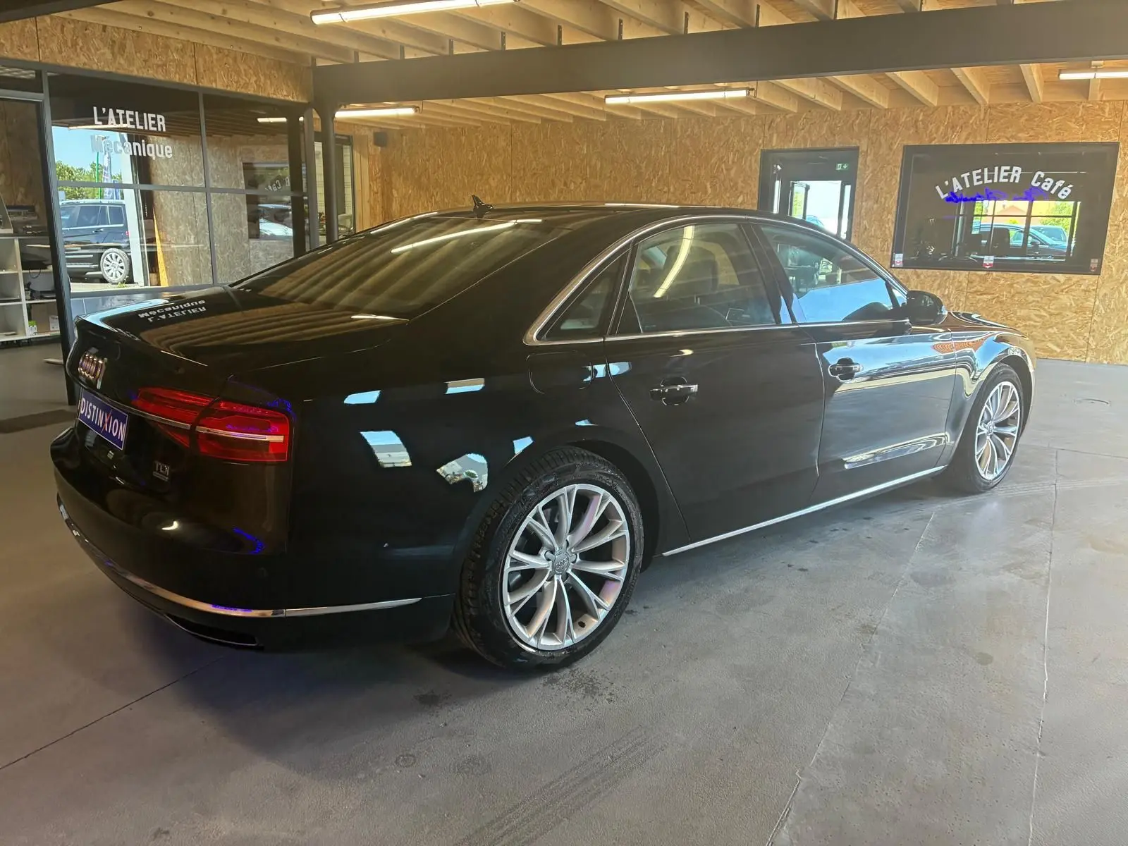 Audi A8 3.0 TDI noir vue 3/4 arrière droit dans un garage avec jantes alliage et finition chrome.