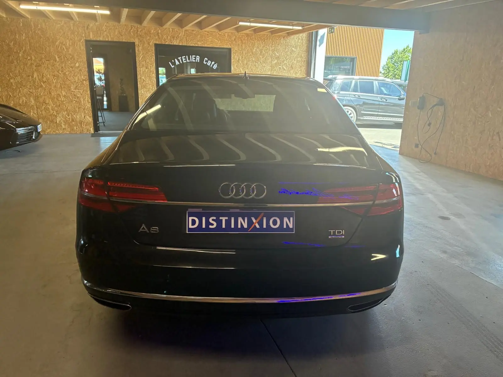 Vue arrière d'une Audi A8 noire 2016 avec logo TDI et plaque Distinxion dans un garage.