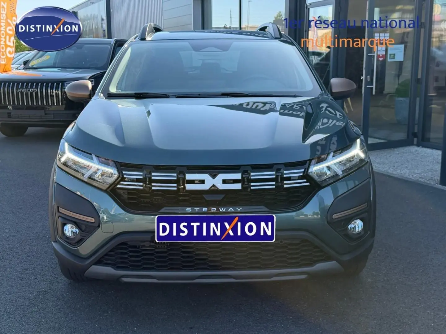 Vue de face d'une Dacia Sandero Stepway 2025 vert cèdre métallisé avec calandre noire et feux LED allumés.