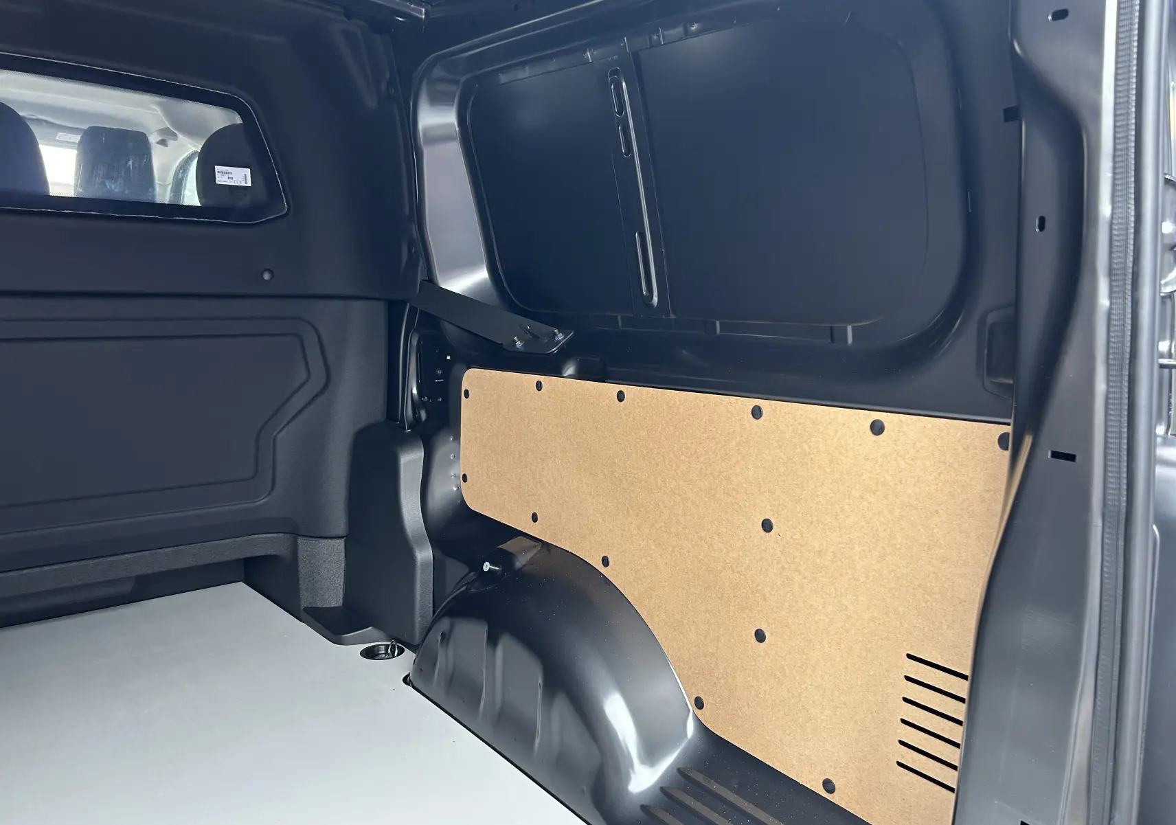 Vue intérieure côté droit de la cabine approfondie grise titane du Citroën Jumpy Long L3 avec cloison en bois et espace de chargement.