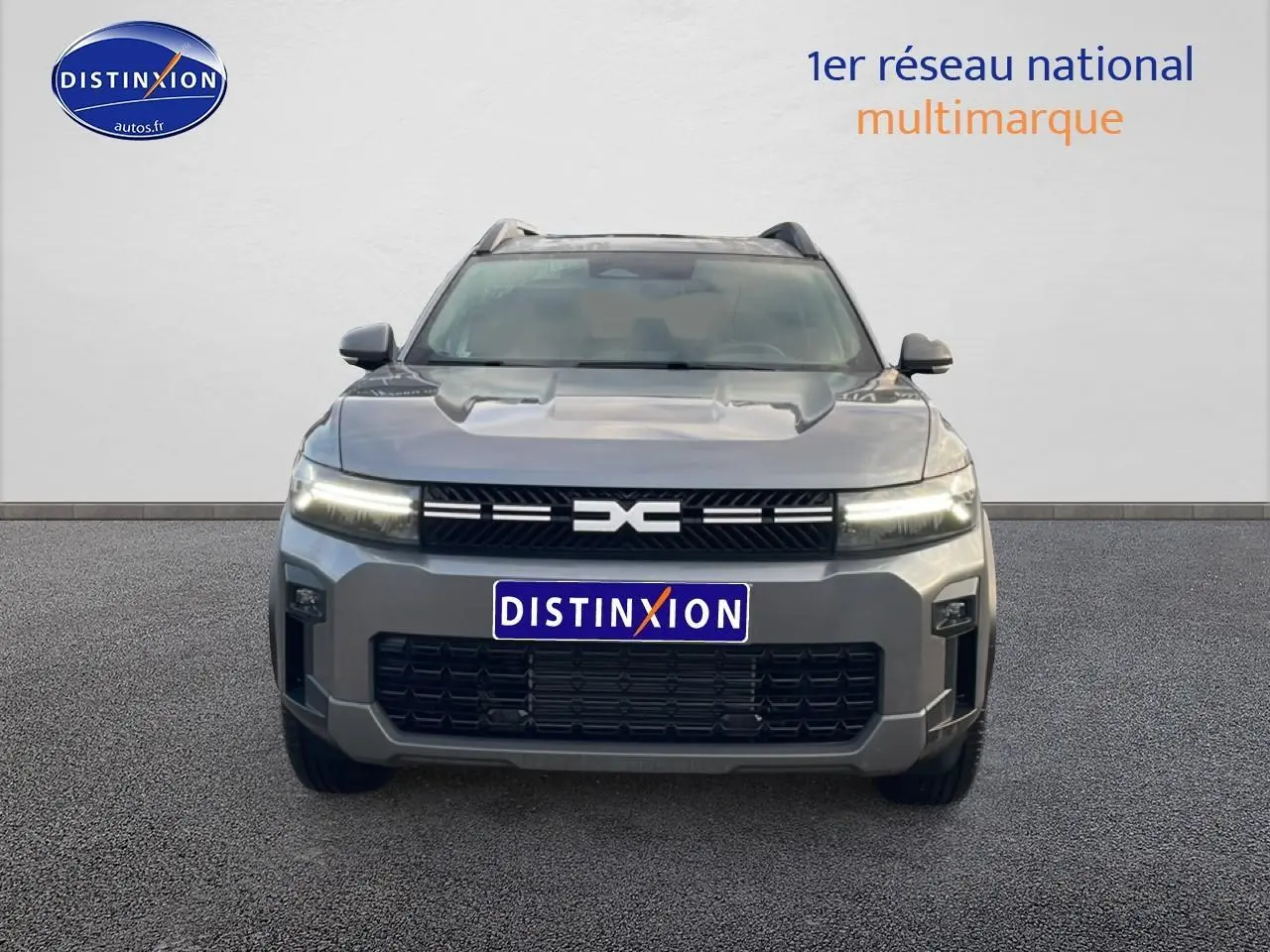 Vue avant du Dacia Bigster gris schiste 2025 avec calandre noire et phares LED allumés.